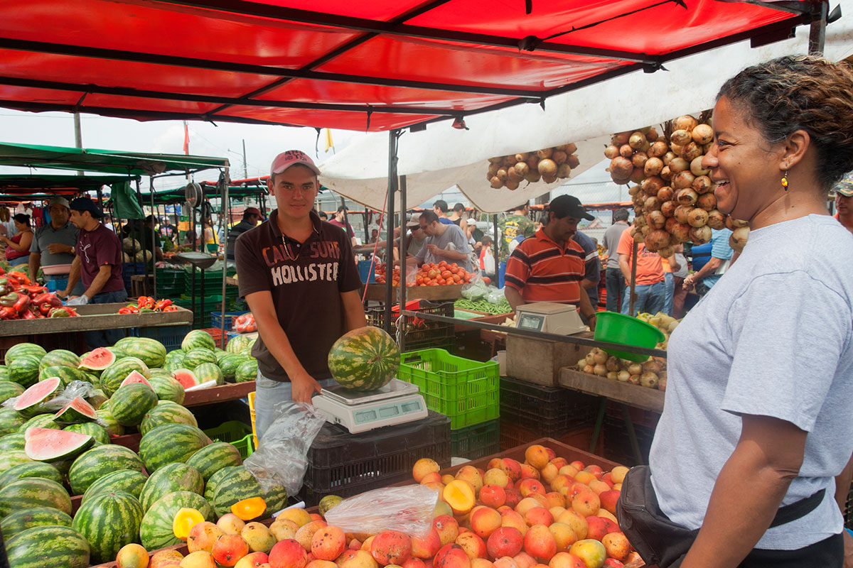A woman purchases product from a man at the farmer’s market
